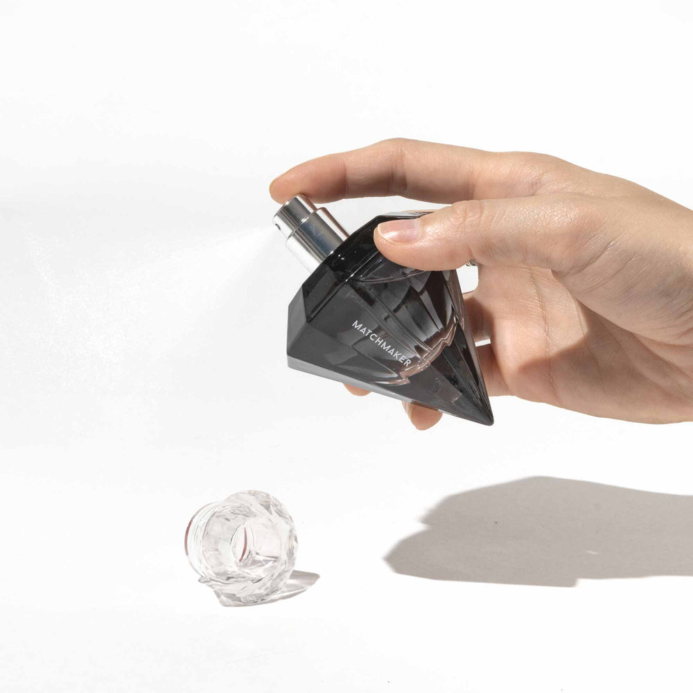 Hand holding a full sized bottle of Eye of Love's Matchmaker Black Diamond pheromone perfume