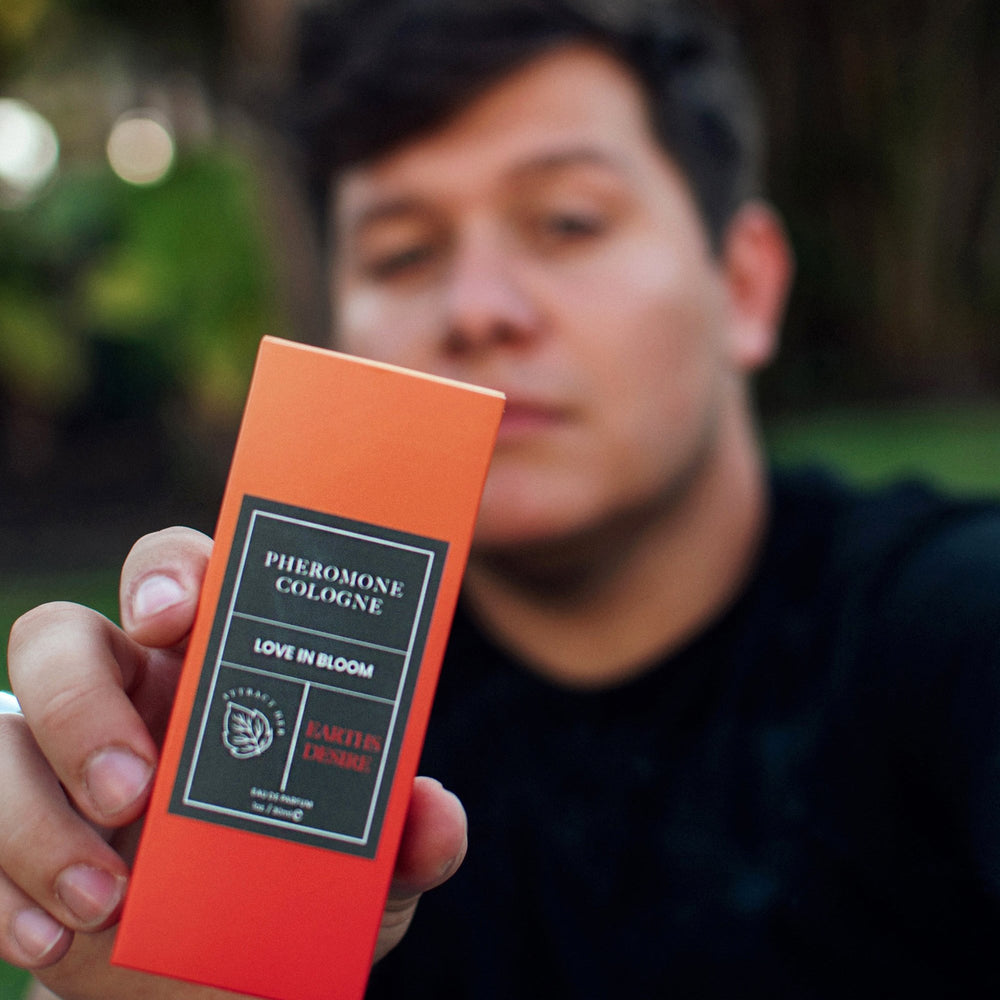 Blurred male holding a bottle of Eye of Love's Earth's Desire pheromone cologne to the camera