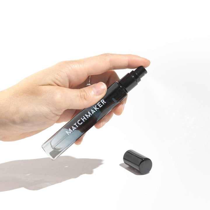 Hand holding a travel sized bottle of Eye of Love's Matchmaker Black Diamond pheromone cologne